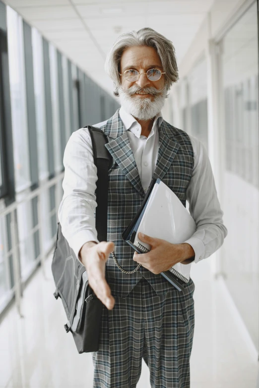 a man with greying hair wearing glasses and a suit and carrying a book in his hands