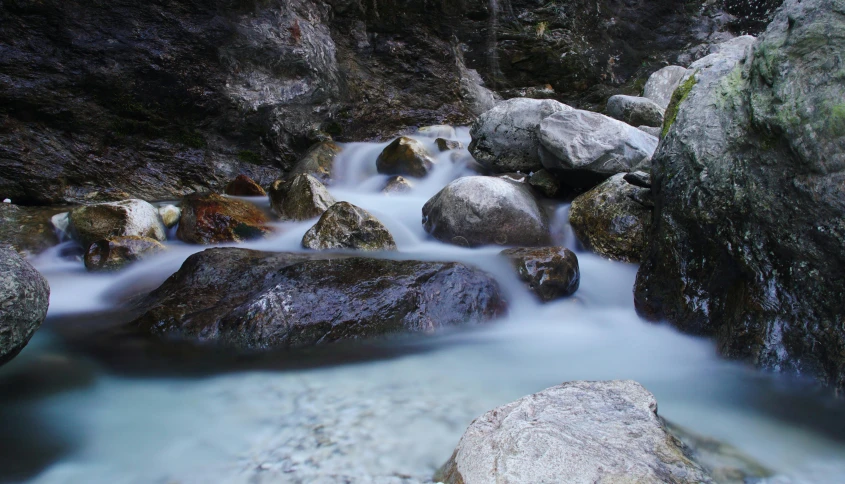 some rocks are in the water near a stream