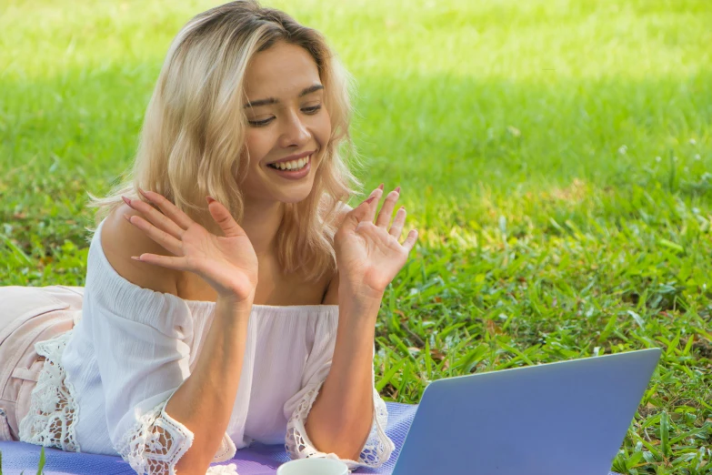 a woman laying in the grass using her laptop