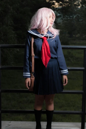 a girl in a school uniform poses by the railing