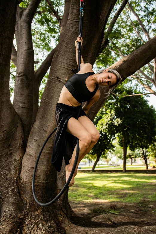 a woman hanging from a hoop, suspended on a tree