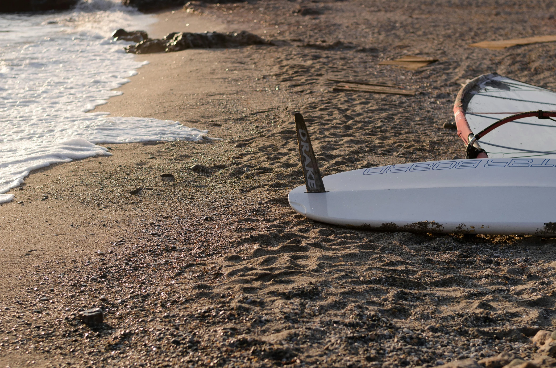 a surfboard sitting on a sandy beach next to the ocean