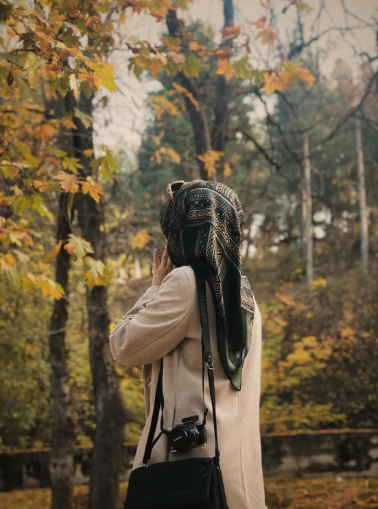 a person that is walking in a park talking on her cell phone