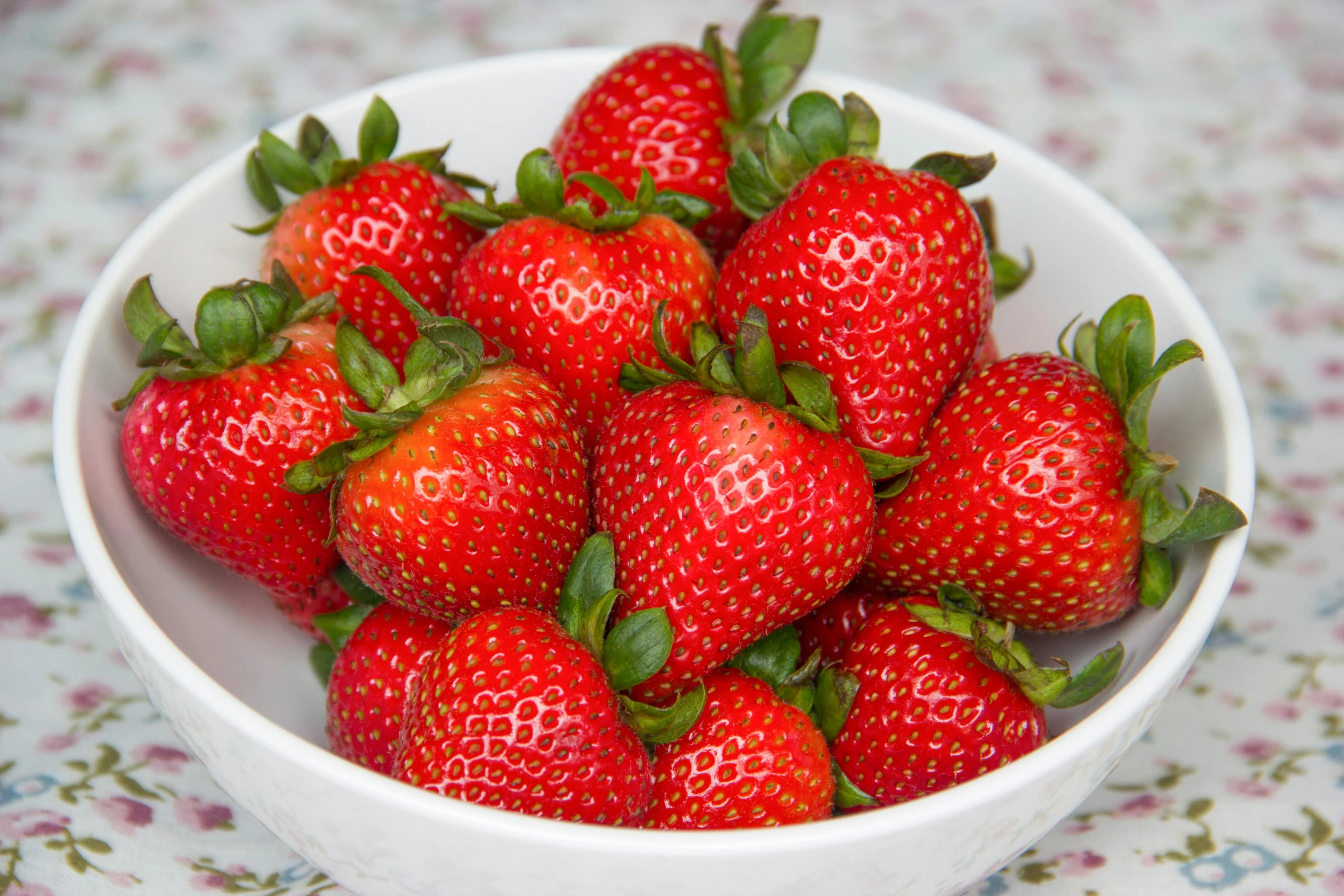 a bowl full of strawberries sitting on a table