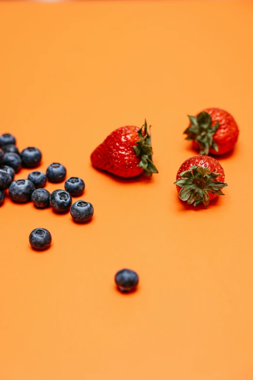 blueberries and strawberries on an orange background
