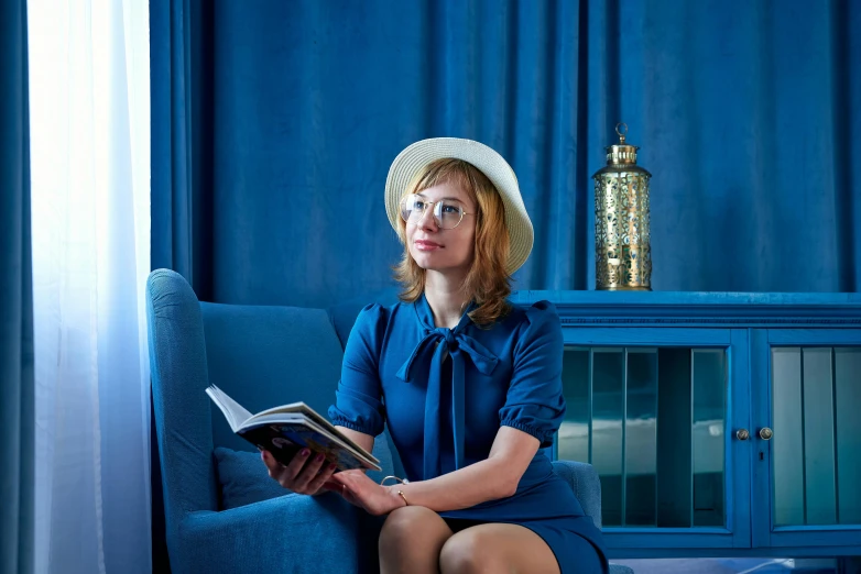 a woman sits on a couch while reading a book