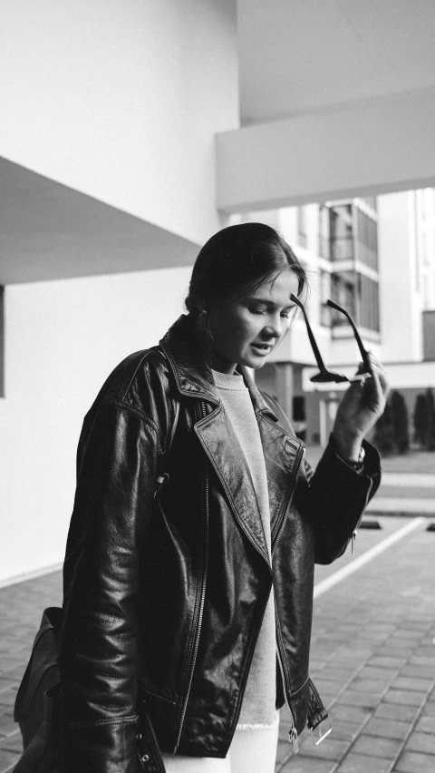 a black and white po of a girl standing outside with her cell phone