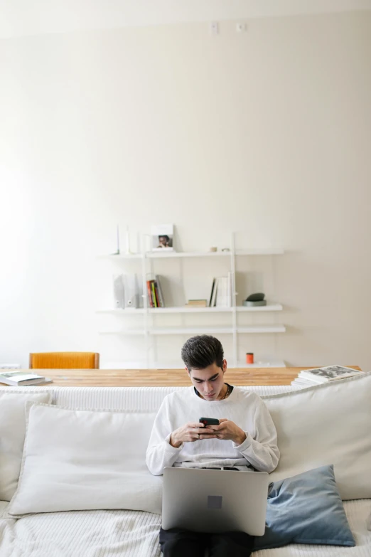 a man is sitting on the sofa and looking at his phone