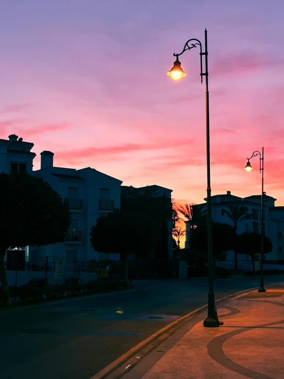 a bright sunset shines on a street lamp