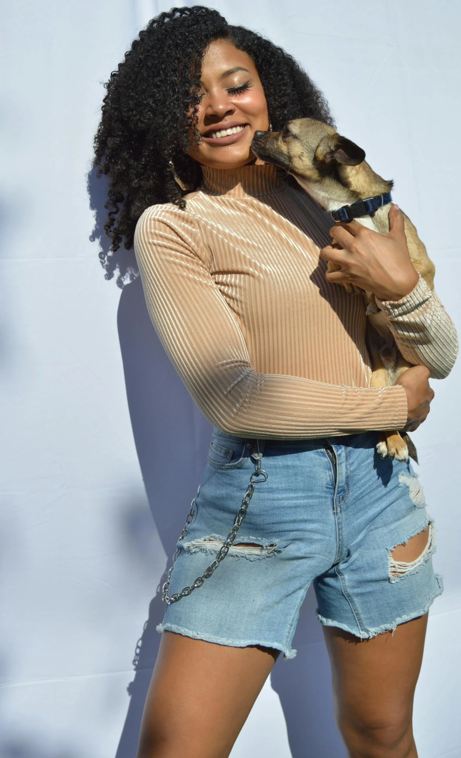 a woman in her shorts holds a little dog