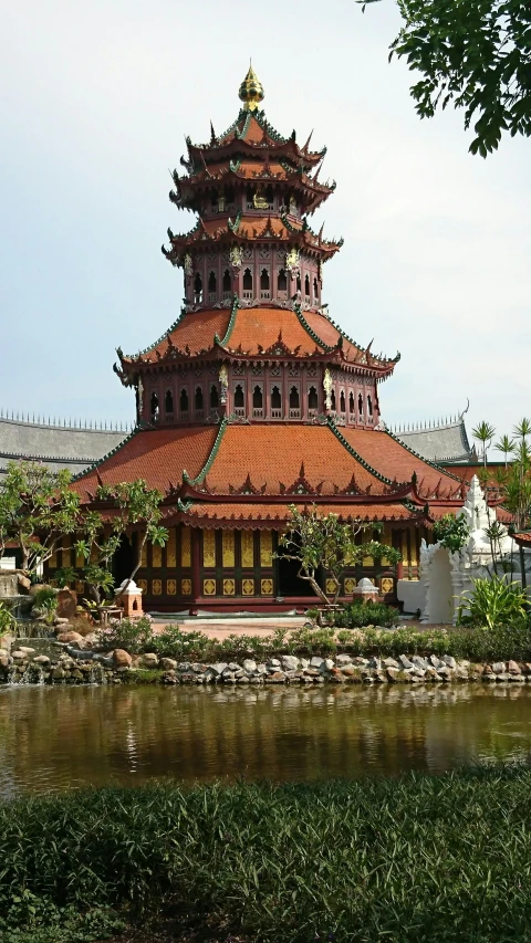 a pagoda that is red and yellow near some water