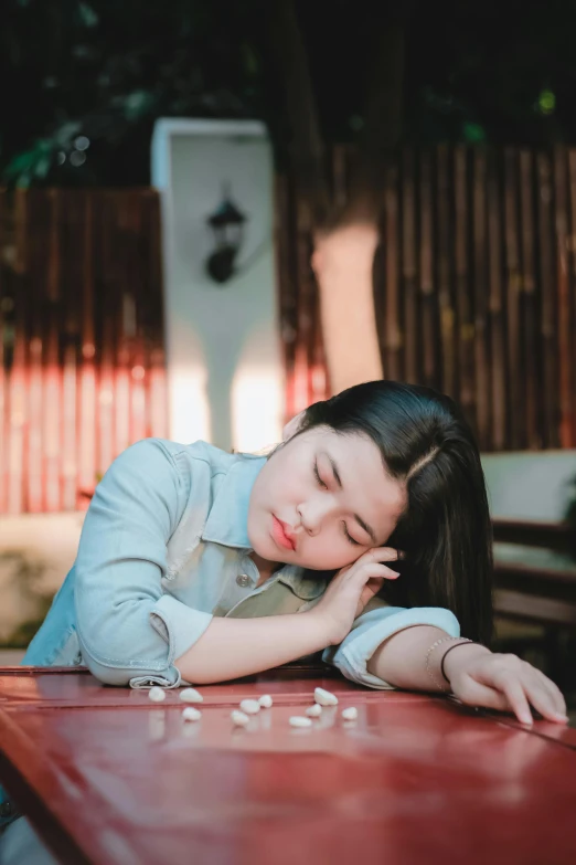 a woman laying down at a red table next to a bottle