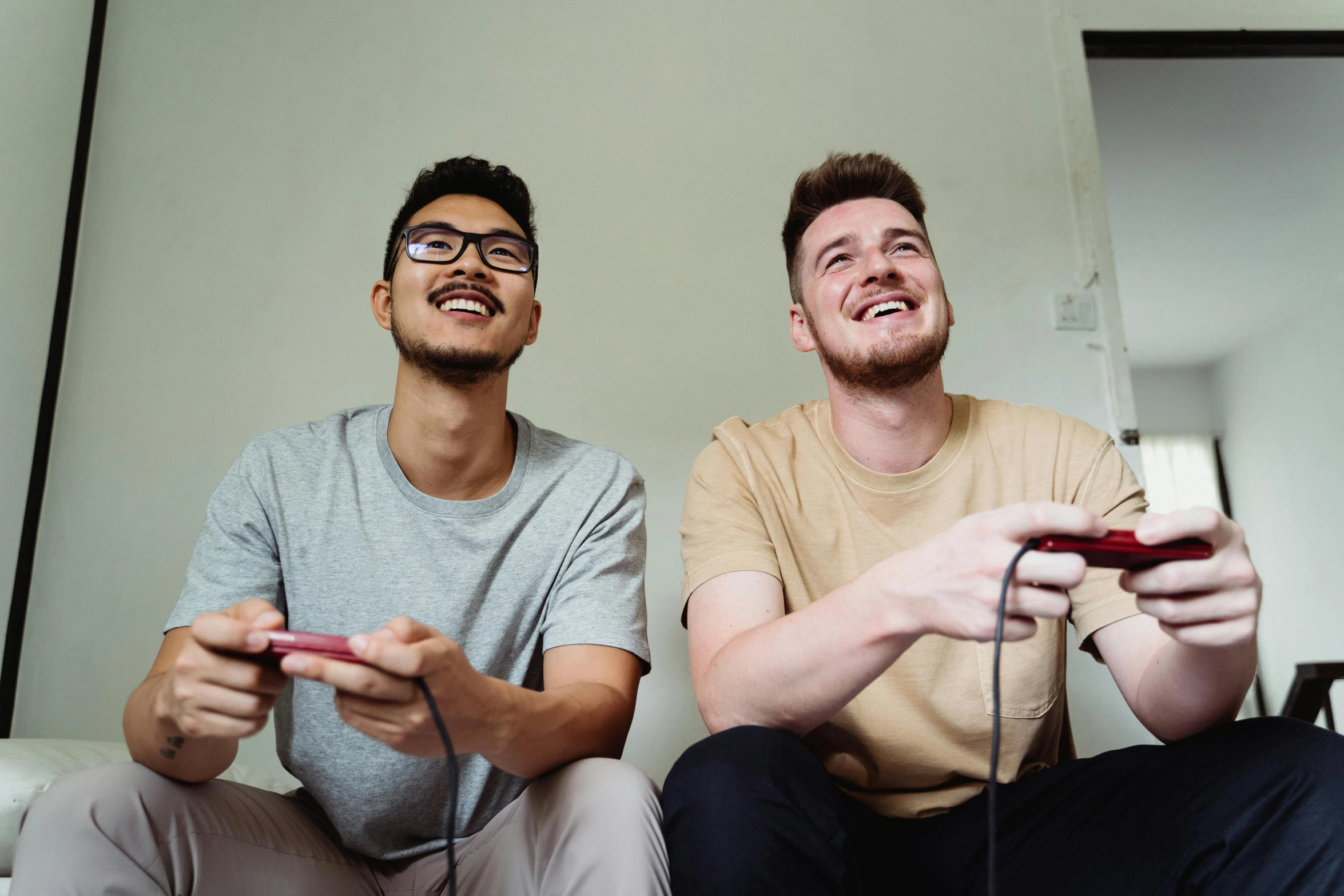 two men sitting down and one holding a remote