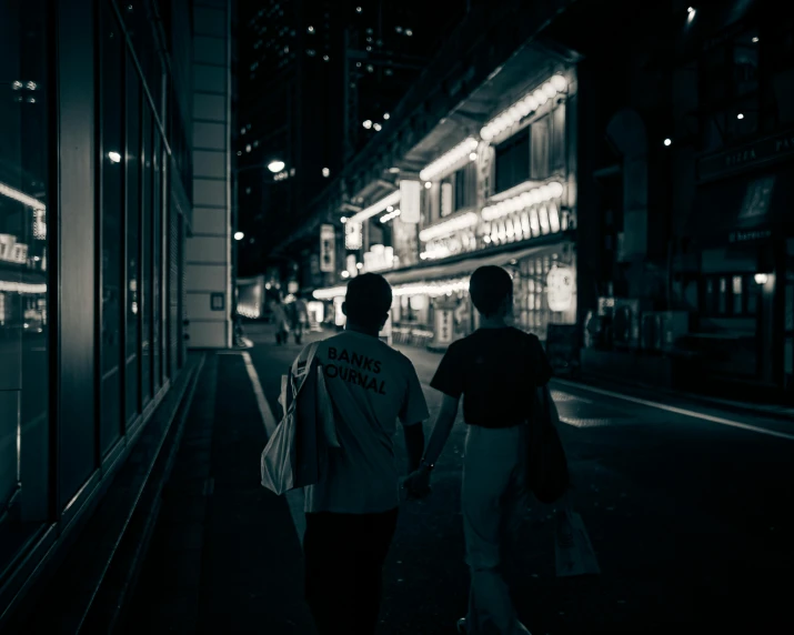 two people walk down the street near a building