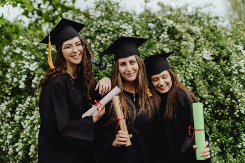 three young graduates with a green book in their hands