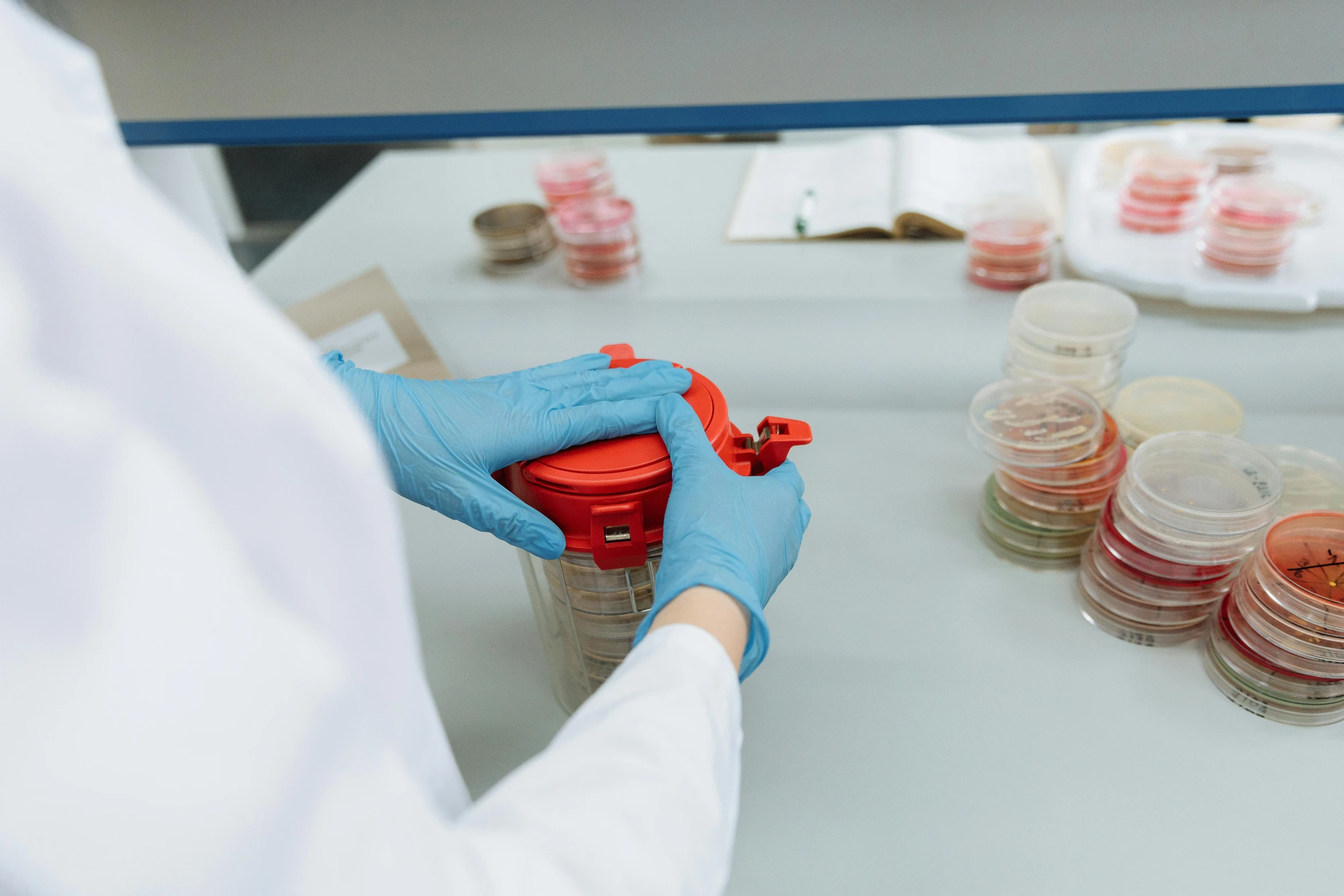 a person with blue gloves and a red jar