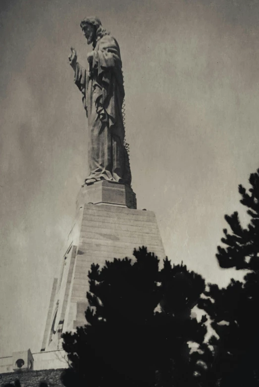 a black and white po of the christ statue in front of trees