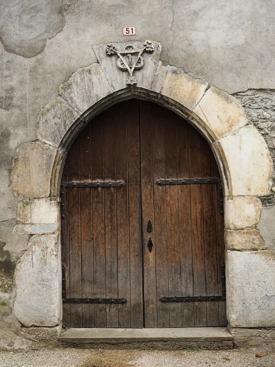 two large, brown doors and two carved heads are on the outside of this building