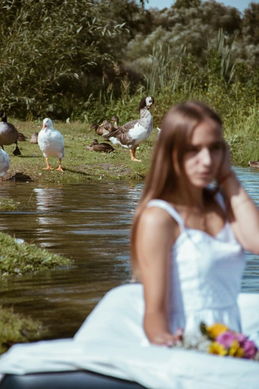 there are many ducks and geese near a woman on the phone