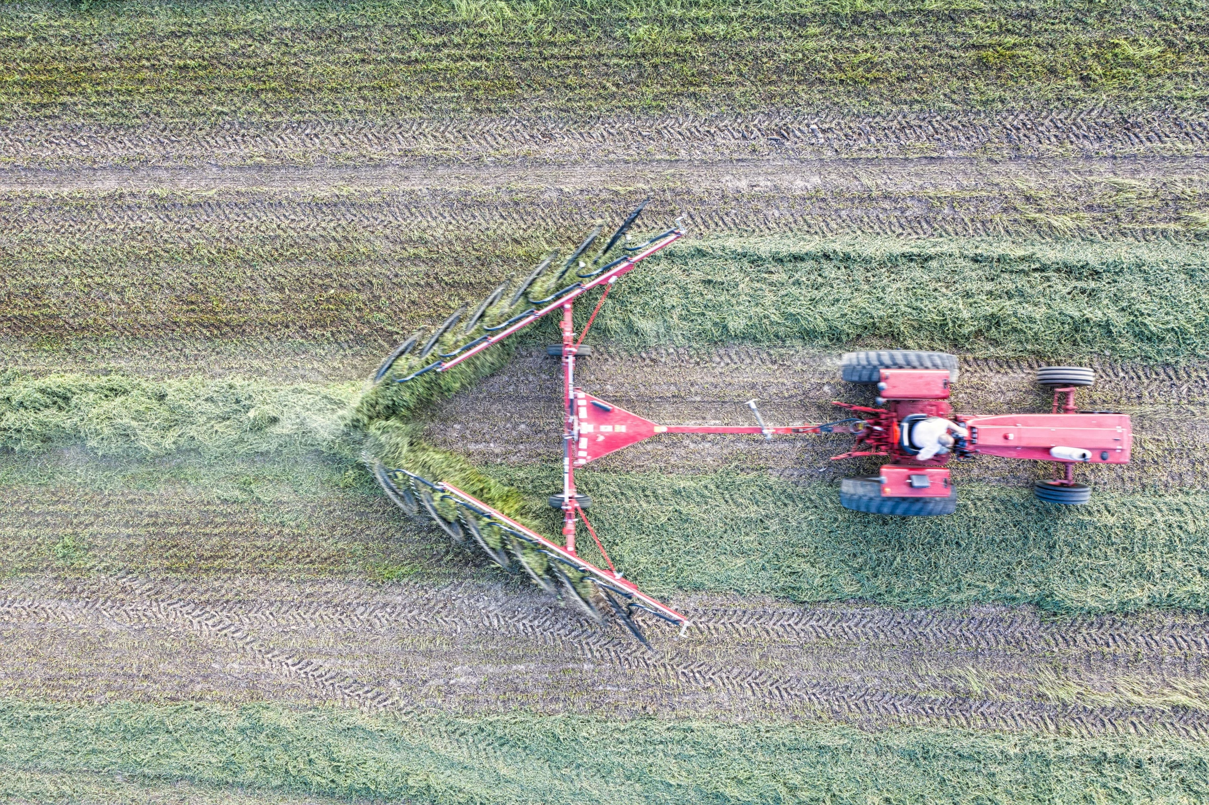 a tractor is  some grass on a farm