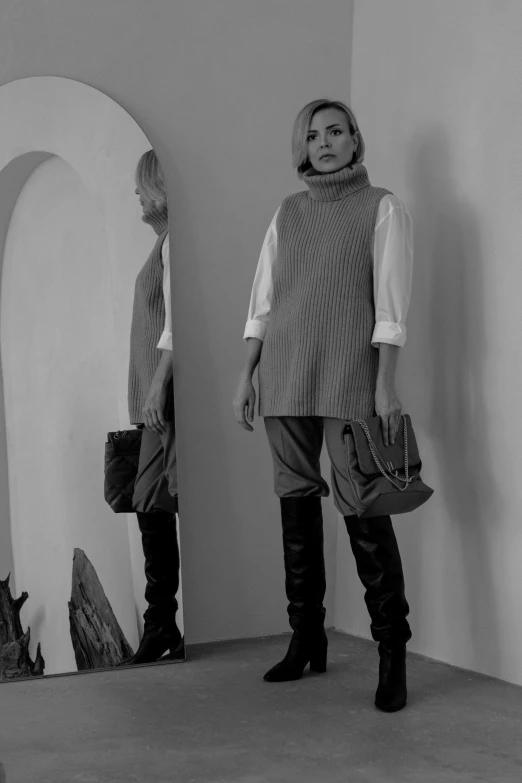 two women in sweaters and black boots are looking at their own mirror