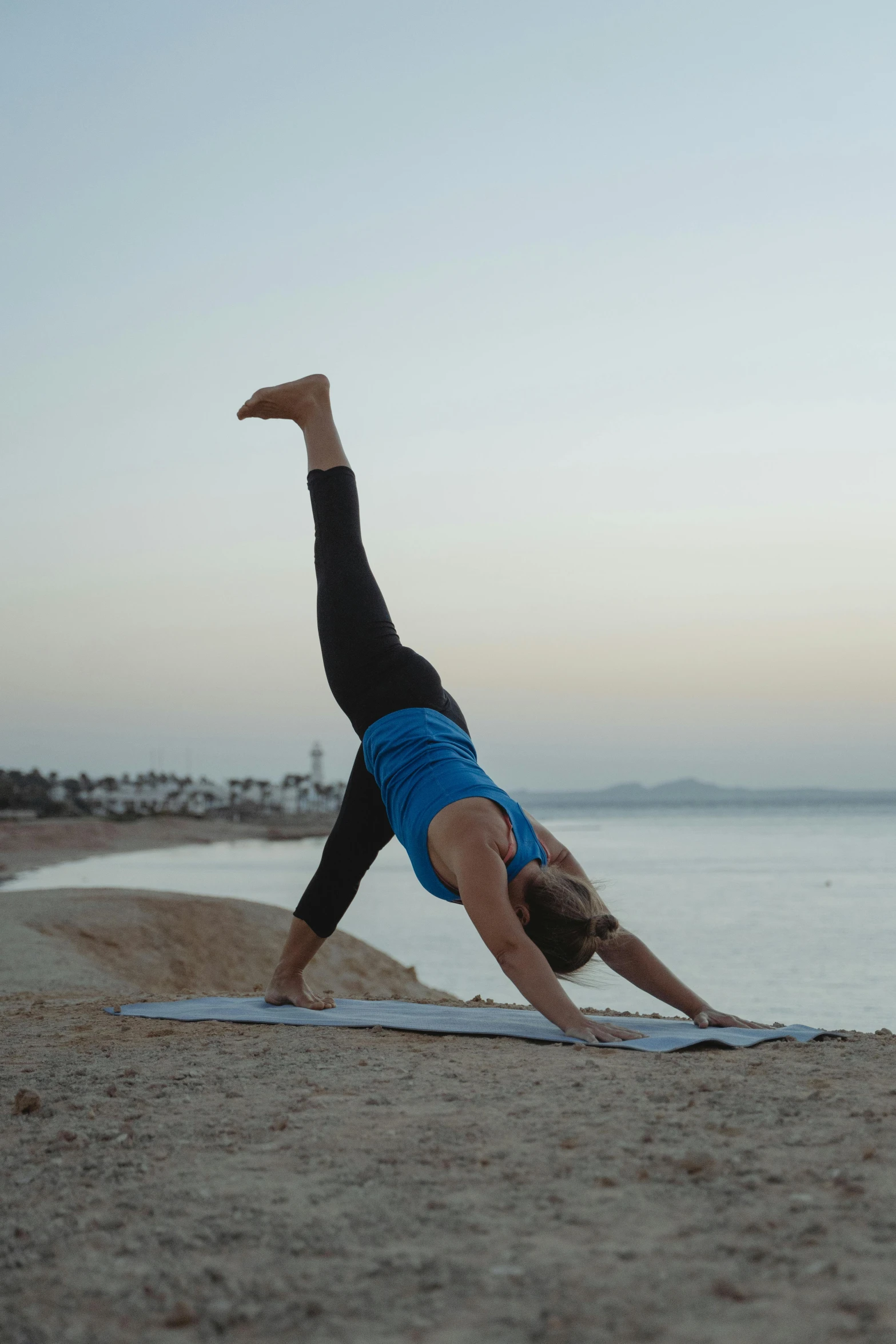 woman on the beach doing a plank pose on her yoga mat