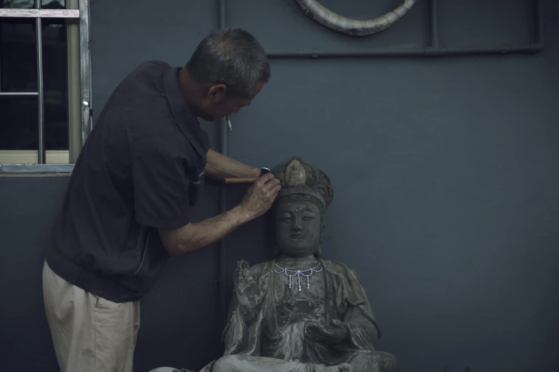 an older man shaving the statue outside of a building