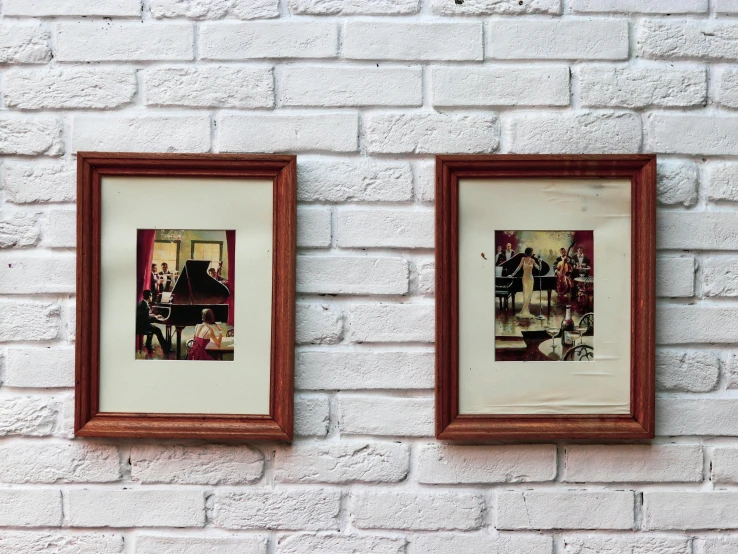 two framed pos hang on a brick wall