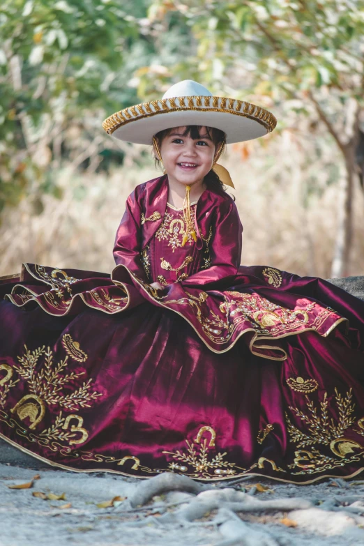 a girl in a mexican style dress is sitting on the ground