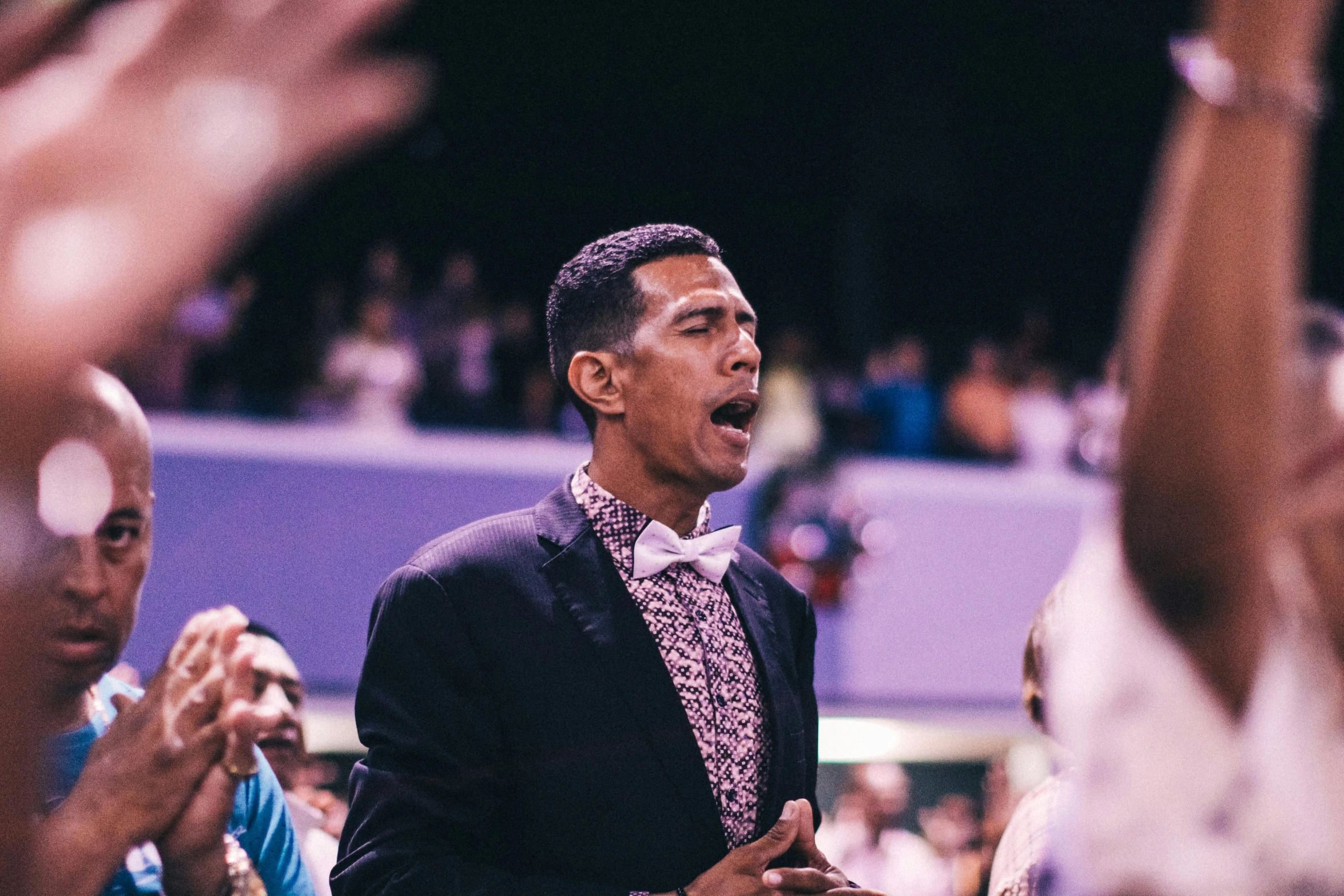 a man standing in front of a crowd wearing a suit