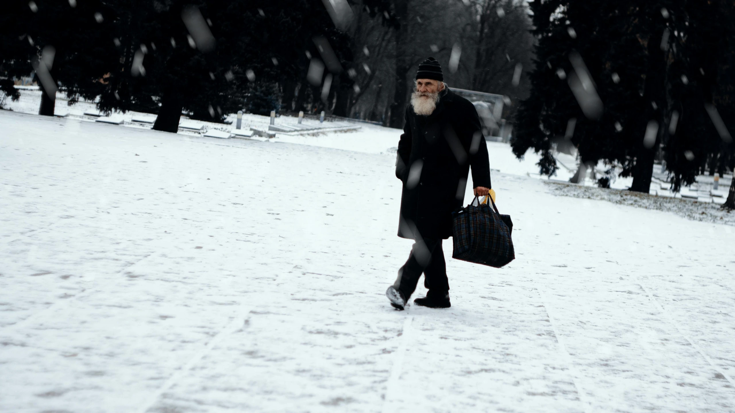 an old man walking in the snow carrying his briefcase