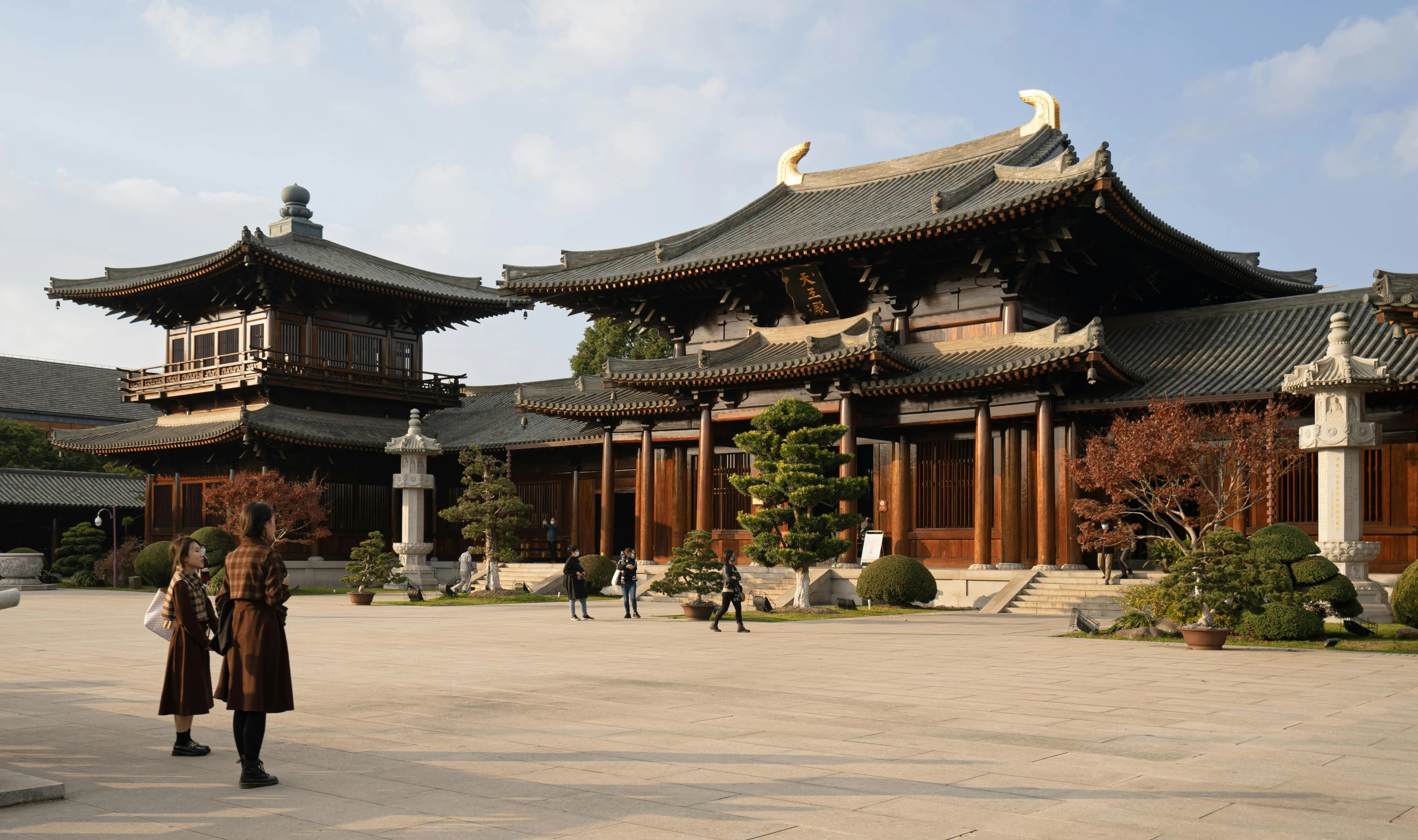 a woman with a black coat standing outside of an ancient building