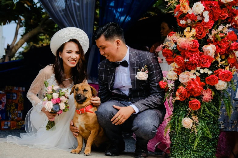 a man and woman in wedding clothes sitting with a dog