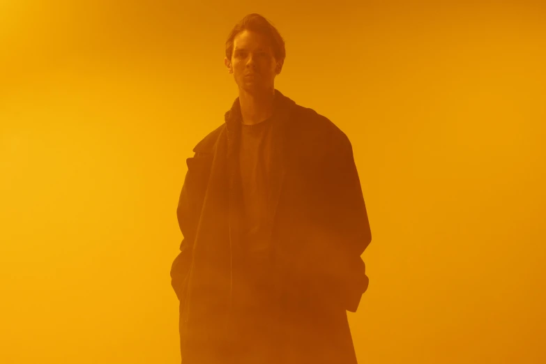 a man is standing in a bright yellow smoke