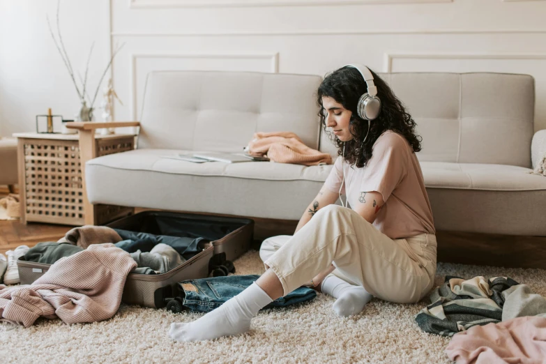 a woman sits on the floor listening to her headphones