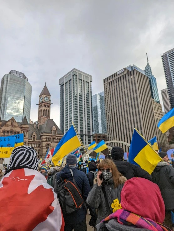 people gathered outside some buildings with flag, one in the foreground and another in the background