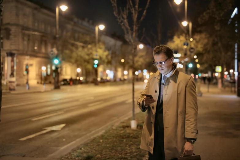 a man standing on the side of a road while using a cell phone