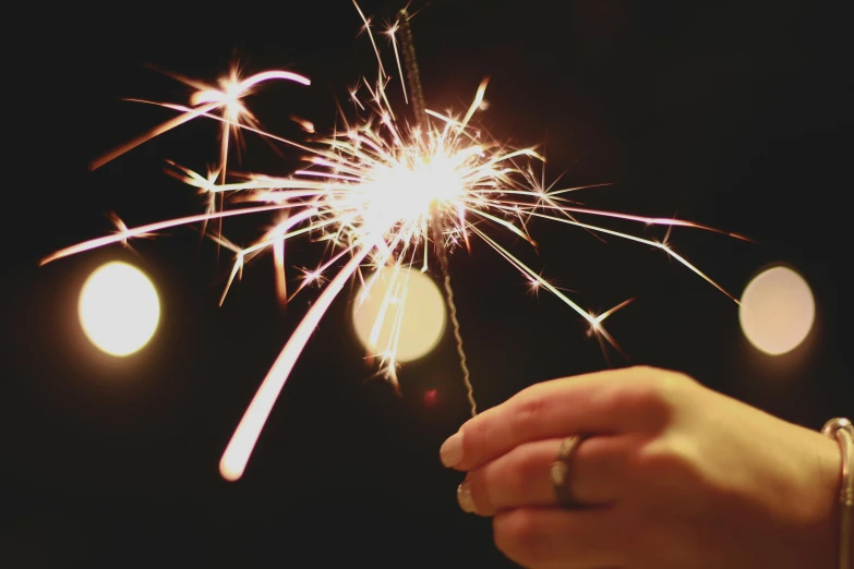 a hand holding a sparkler and a ring