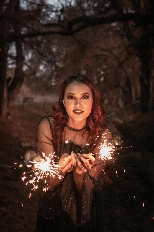 a girl is holding sparklers that are glowing brightly