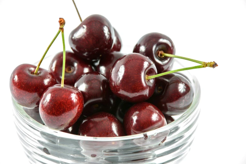 a bowl with cherries in it on a white surface