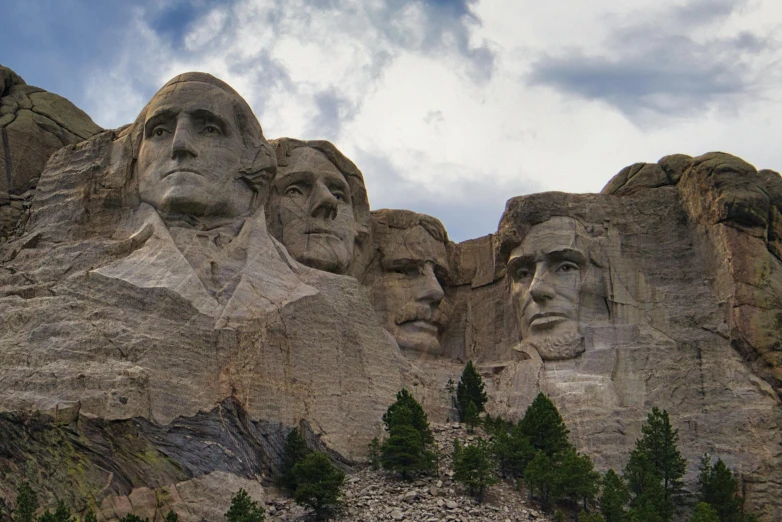 several presidents carved into a mountain under a cloudy sky