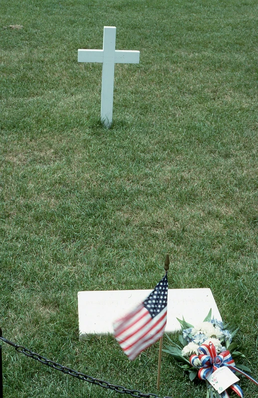 a cemetery with a memorial in the foreground and a us flag laying on the ground