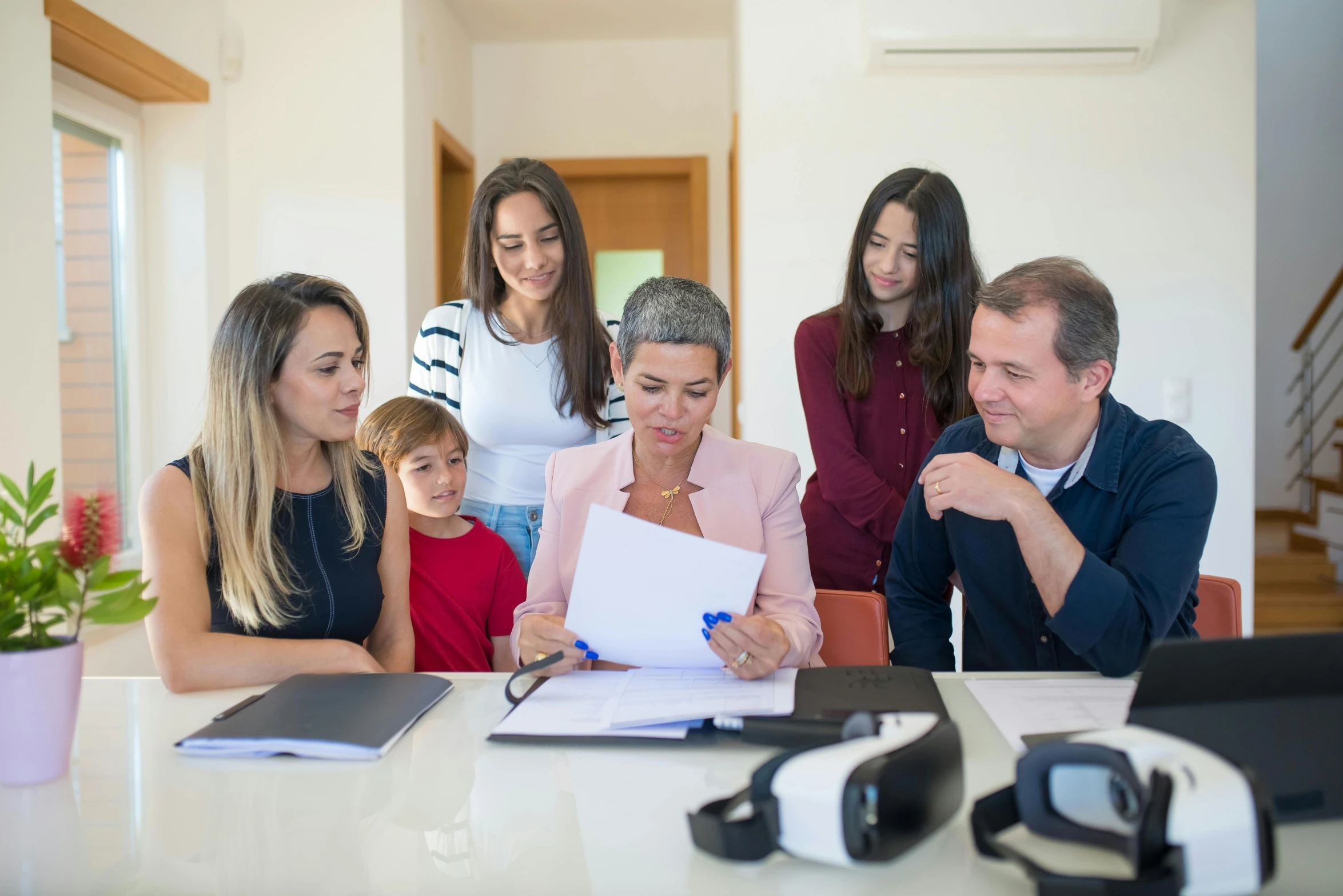 a family is gathered around a desk with a clipboard on it