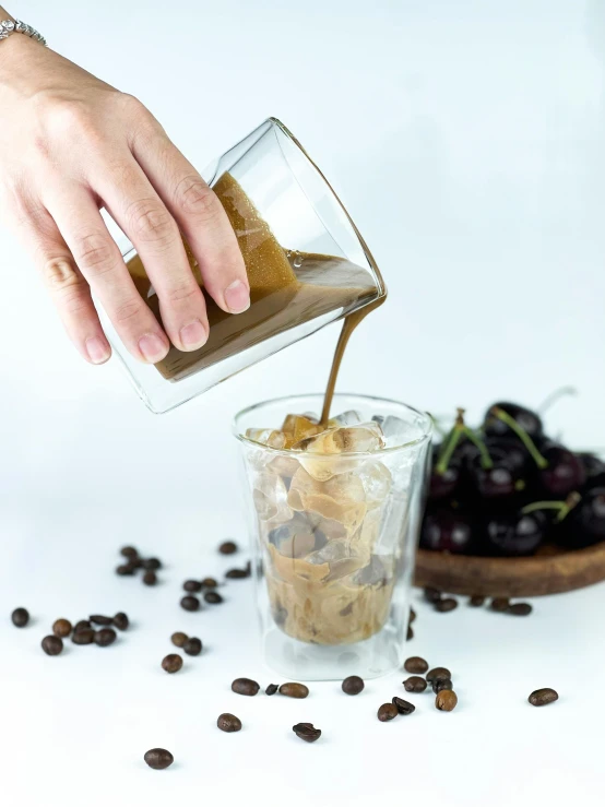 someone pours a drink into a glass filled with coffee beans