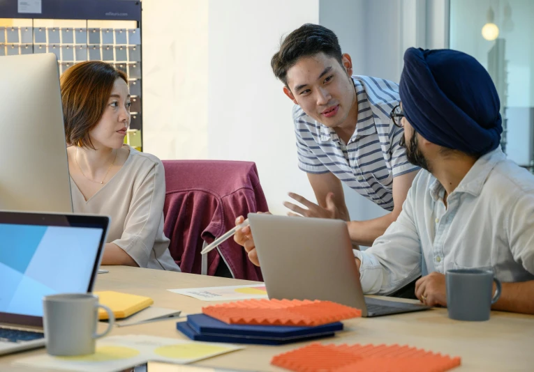 two men and two women talking around a computer