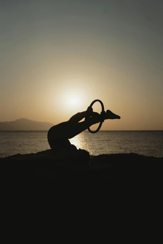 a woman doing a sit - ups with the sun setting behind her