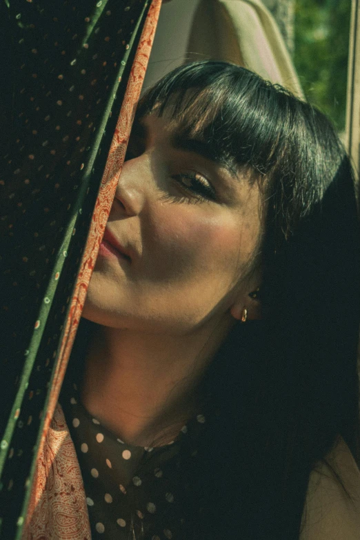 a woman sitting next to a tree with a green umbrella