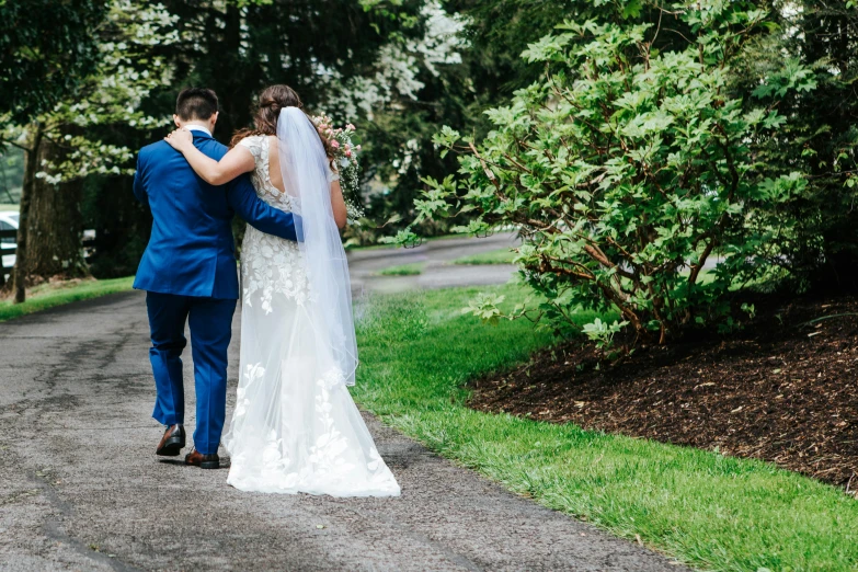 the bride and groom are walking together in the woods