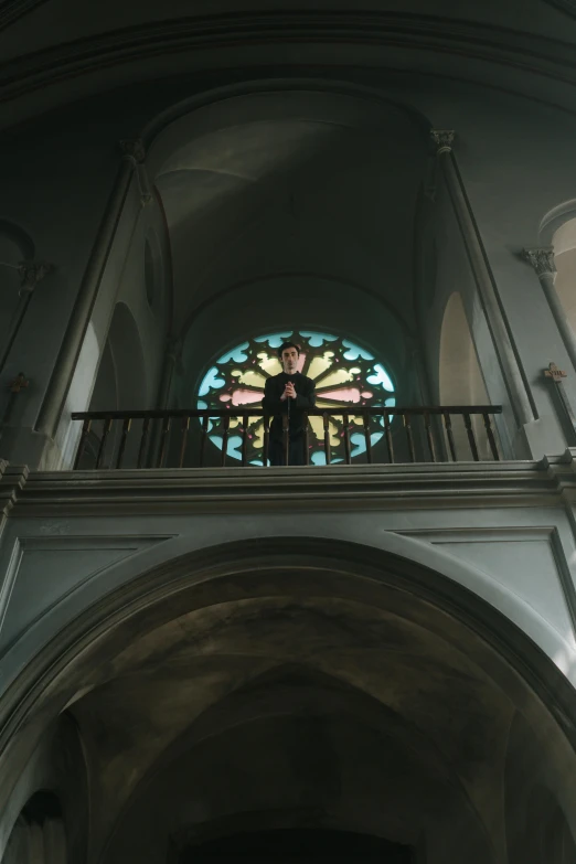 a man standing in a church next to a stained glass window