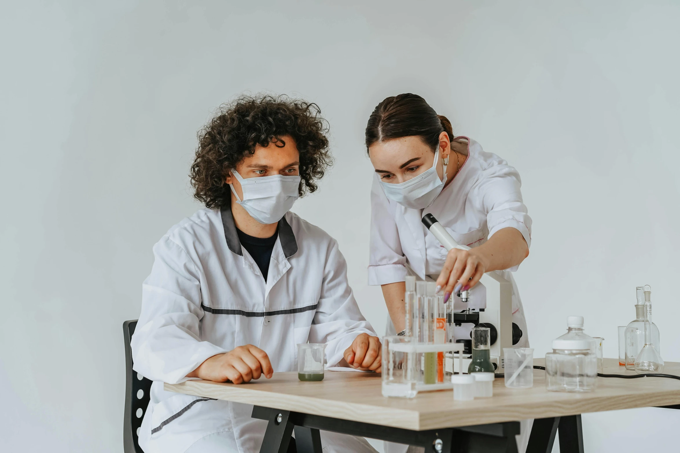 a couple of people in white lab coats working on some sort of substance